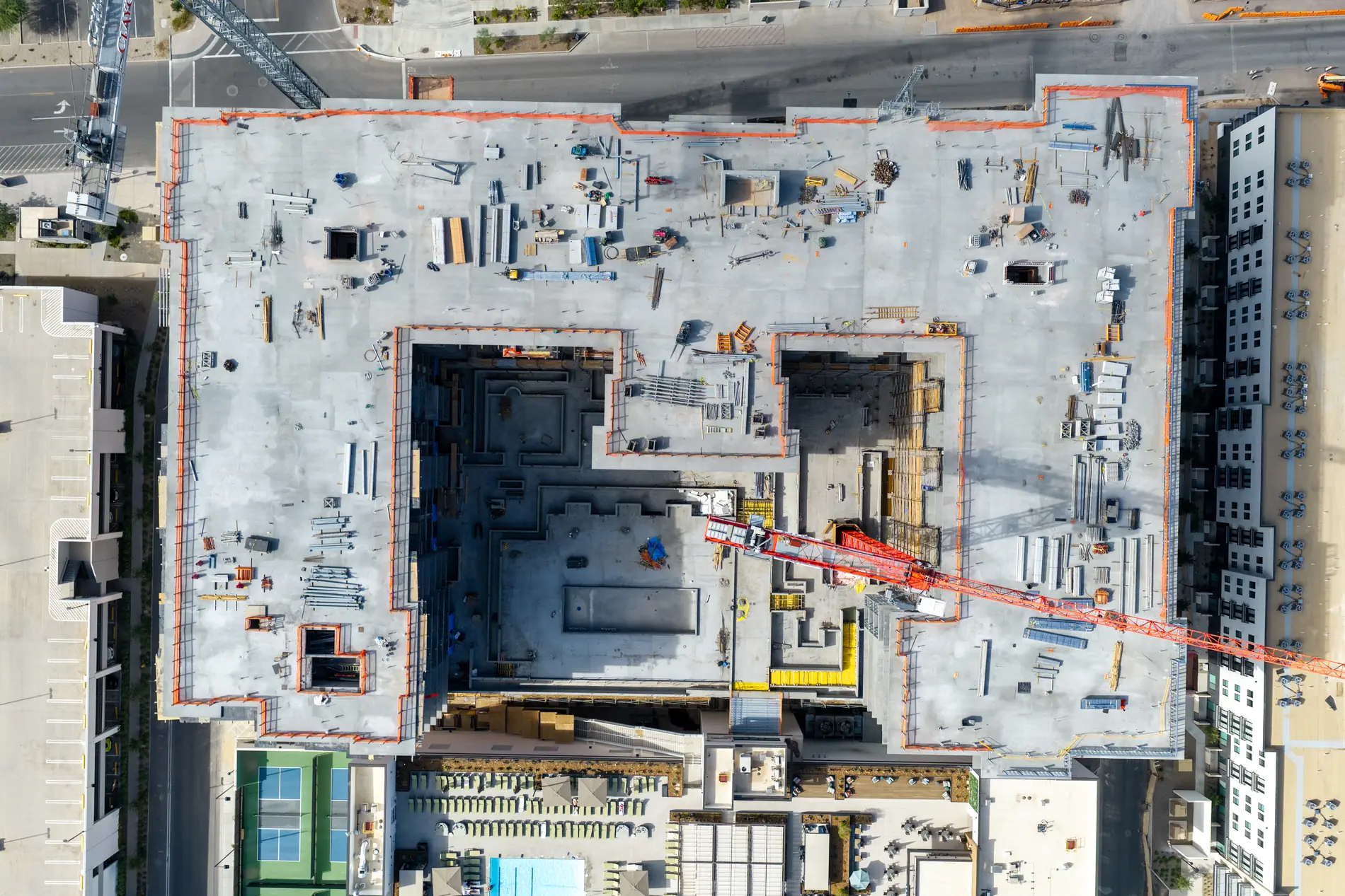 Top-down aerial of the construction deck showing material staging, floor openings and crane position